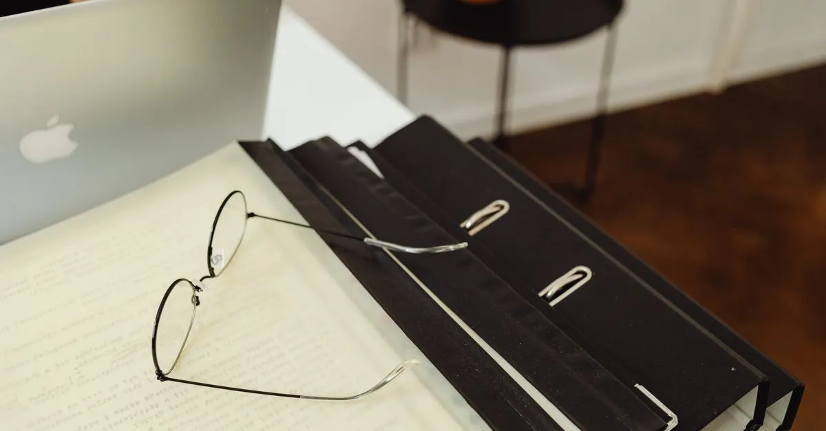 Laptop and stacked paper documents on an office desk before compressing a PDF file
