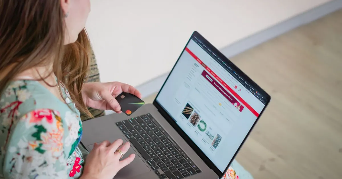 Person holding a credit card while checking an online payment form on a laptop