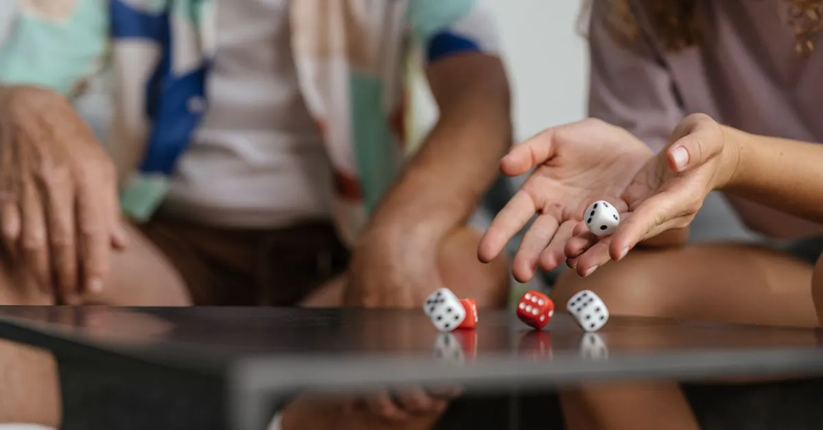 Polyhedral dice scattered across a wooden board game table mid-roll
