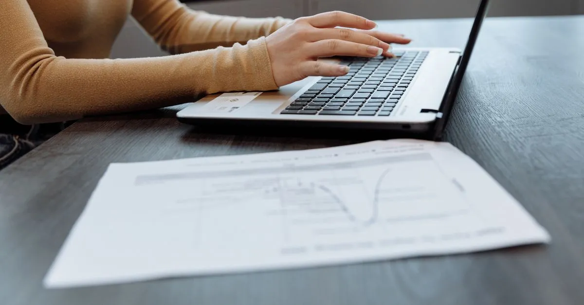 Hands typing on a laptop keyboard while editing a document, find and replace text online