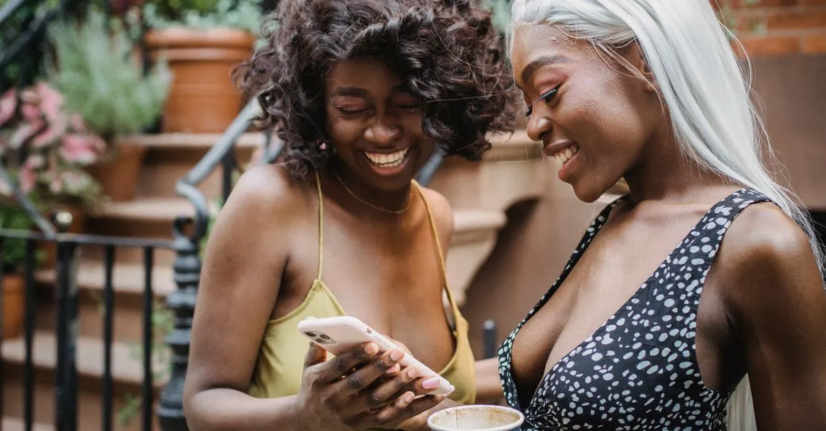 Friends laughing at a phone screen while sharing a meme made with a meme generator