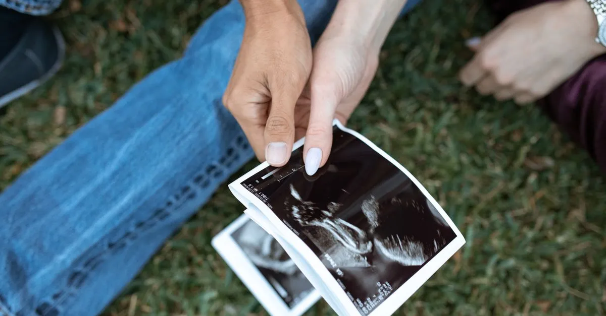 Pregnant woman marking a due date on a wall calendar next to an ultrasound photo